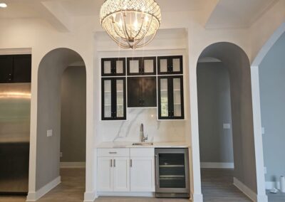 A quartz bar with a sink and faucet. The wall has a full backsplash.